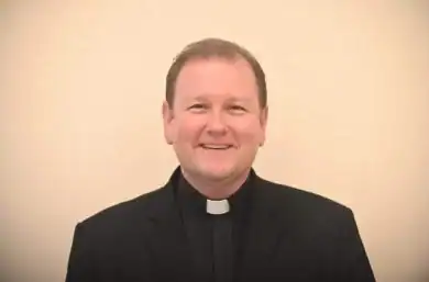 Hombre pastor sonriente en medio de oración o charla religiosa.