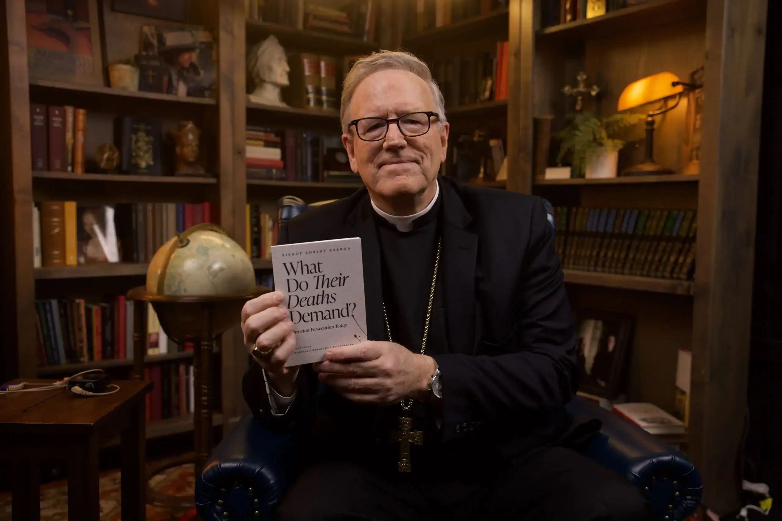 Bishop Barron holding copy of What Do Their Deaths Demand