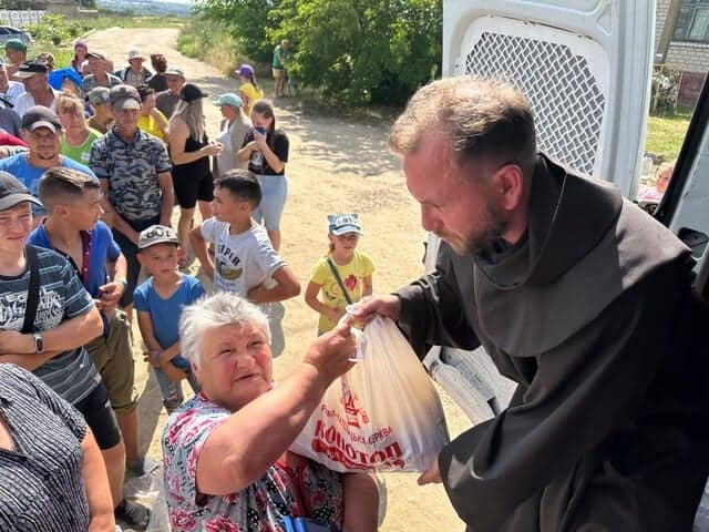 Un sacerdote reparte comida entre la gente en Konotop, 2023
